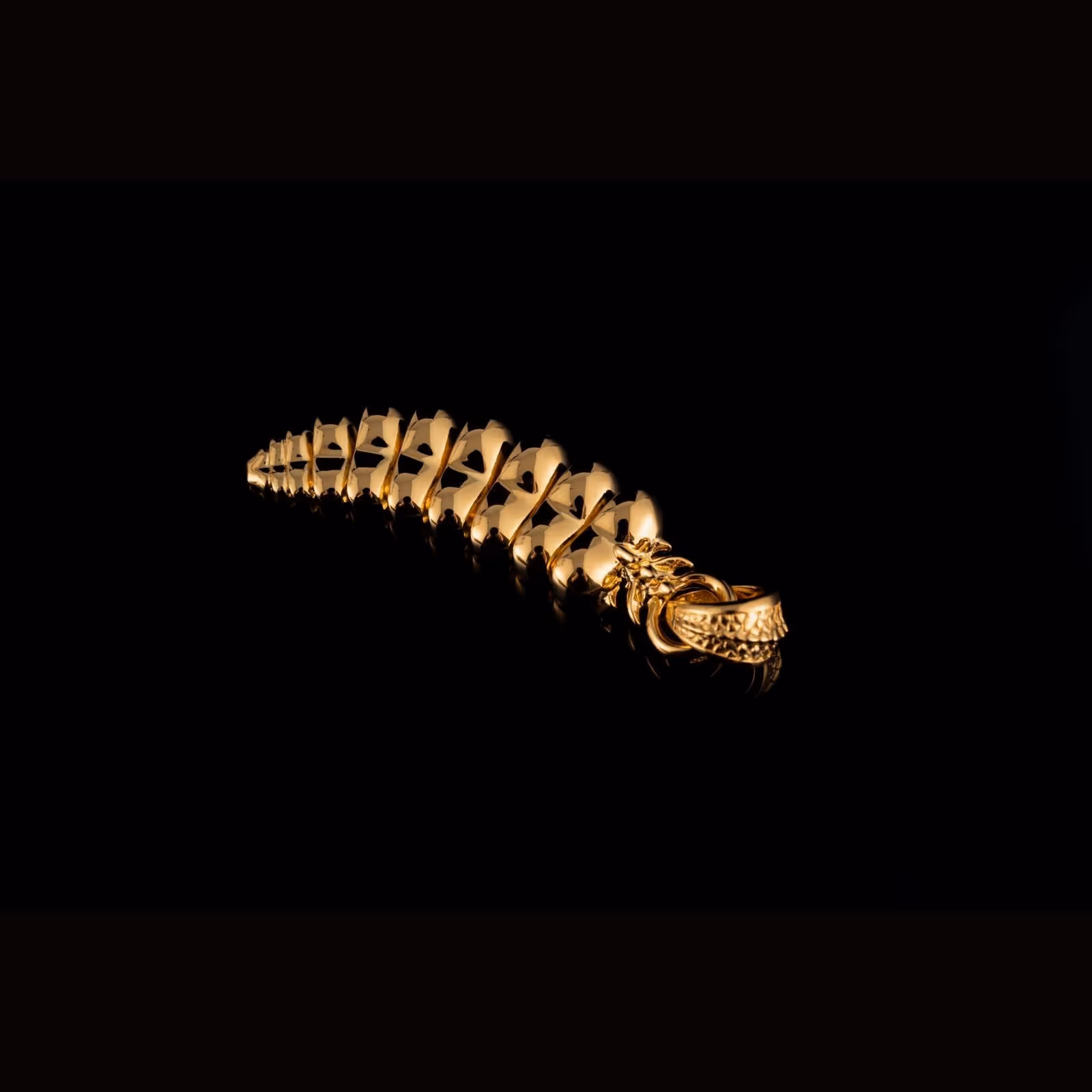 A forged gold pendant, scales catching a warm light